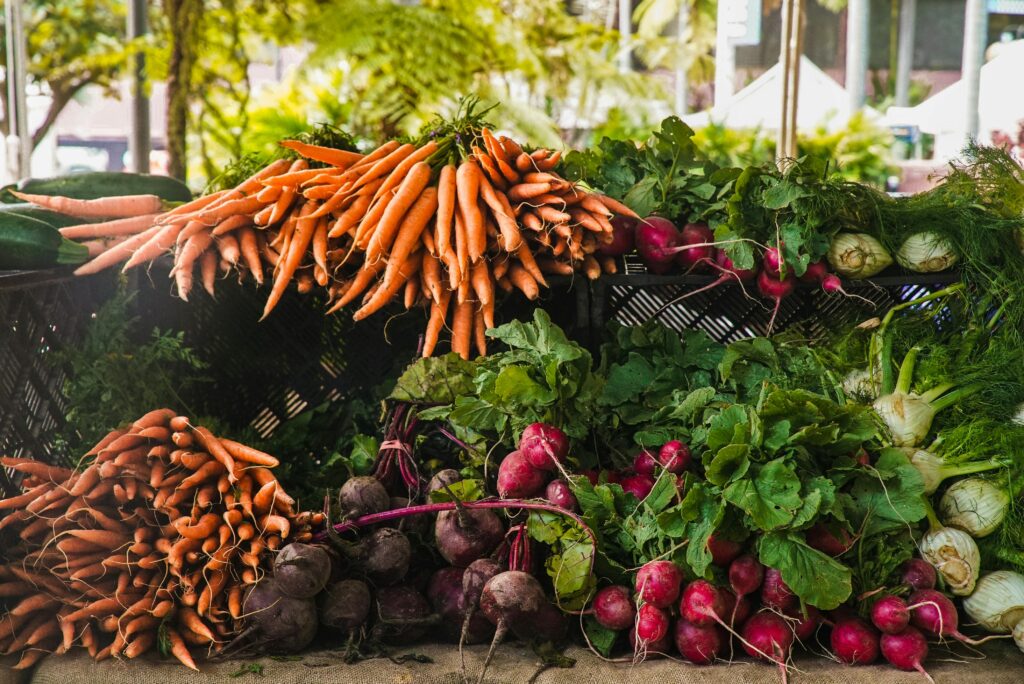 pexels-photo-1656663-1656663 A vibrant display of fresh carrots, radishes, and greens at a local outdoor market.